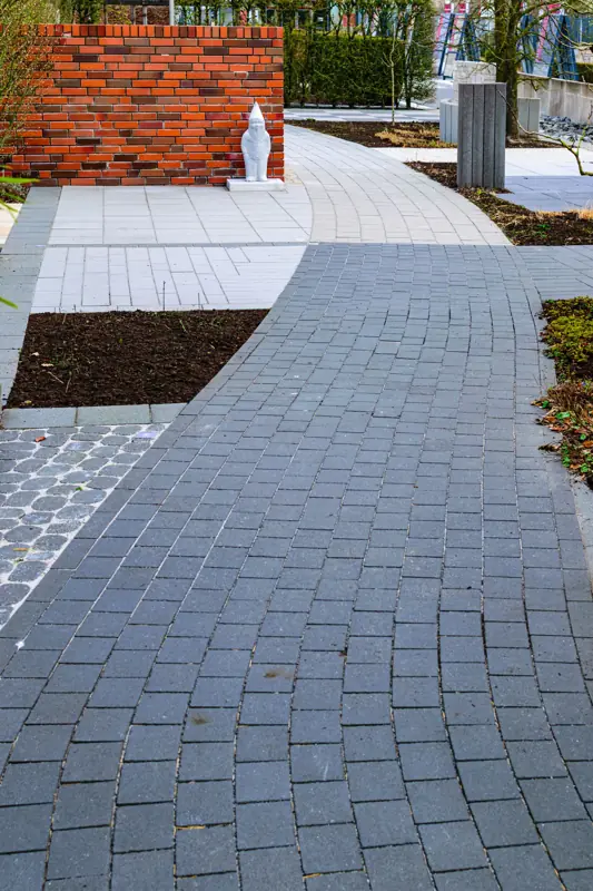 Breed tuinpad van grijze klinkers langs een border