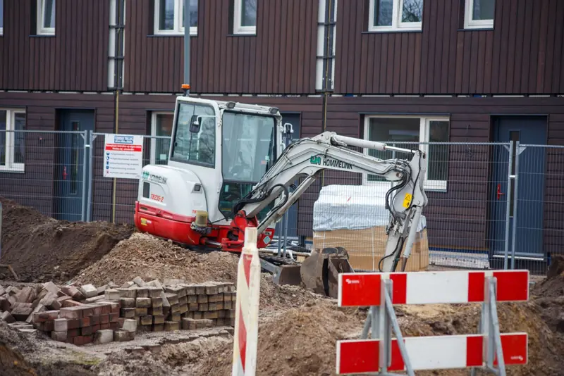 Graafmachine tussen hopen puin op een bouwterrein
